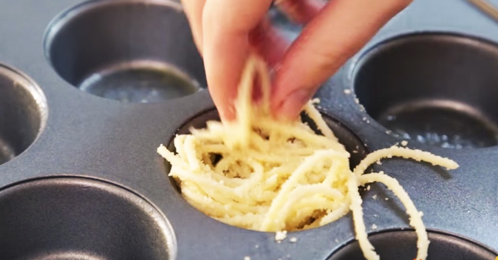 Hun fyller muffinsformen med spaghetti. Det hun lager ser så godt ut!