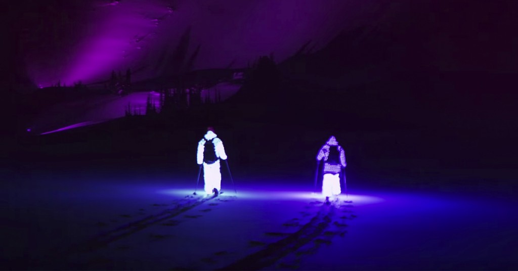 To menn står på ski i mørket, med lysende drakter. Det som skjer er utrolig!